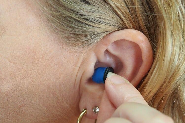 Woman places earplug in her ear