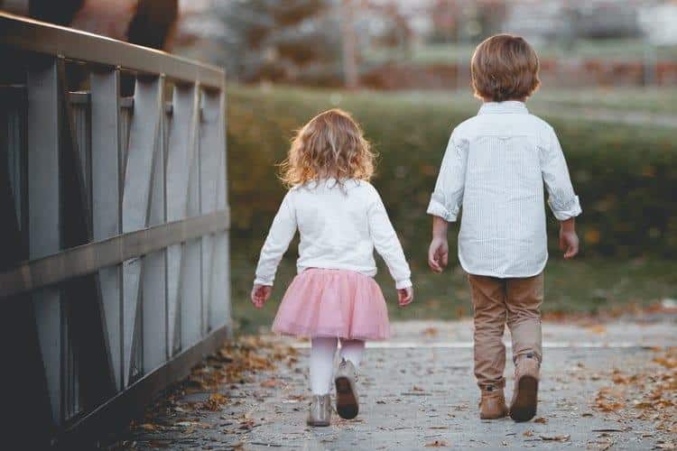 Two children walking on bridge.