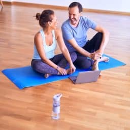 Middle-aged couple sitting together on yoga mat.