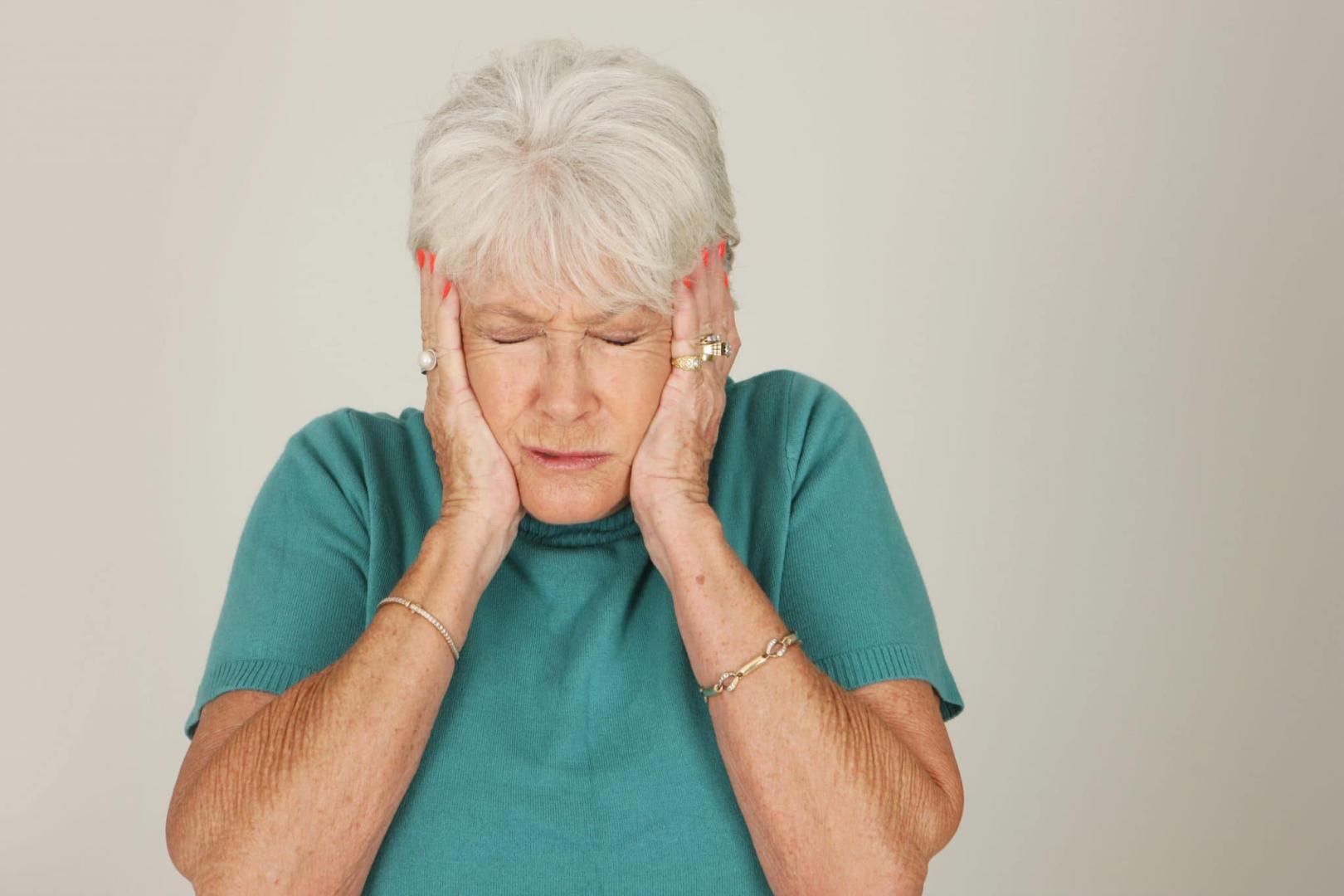 Older woman puts her hands over her ears