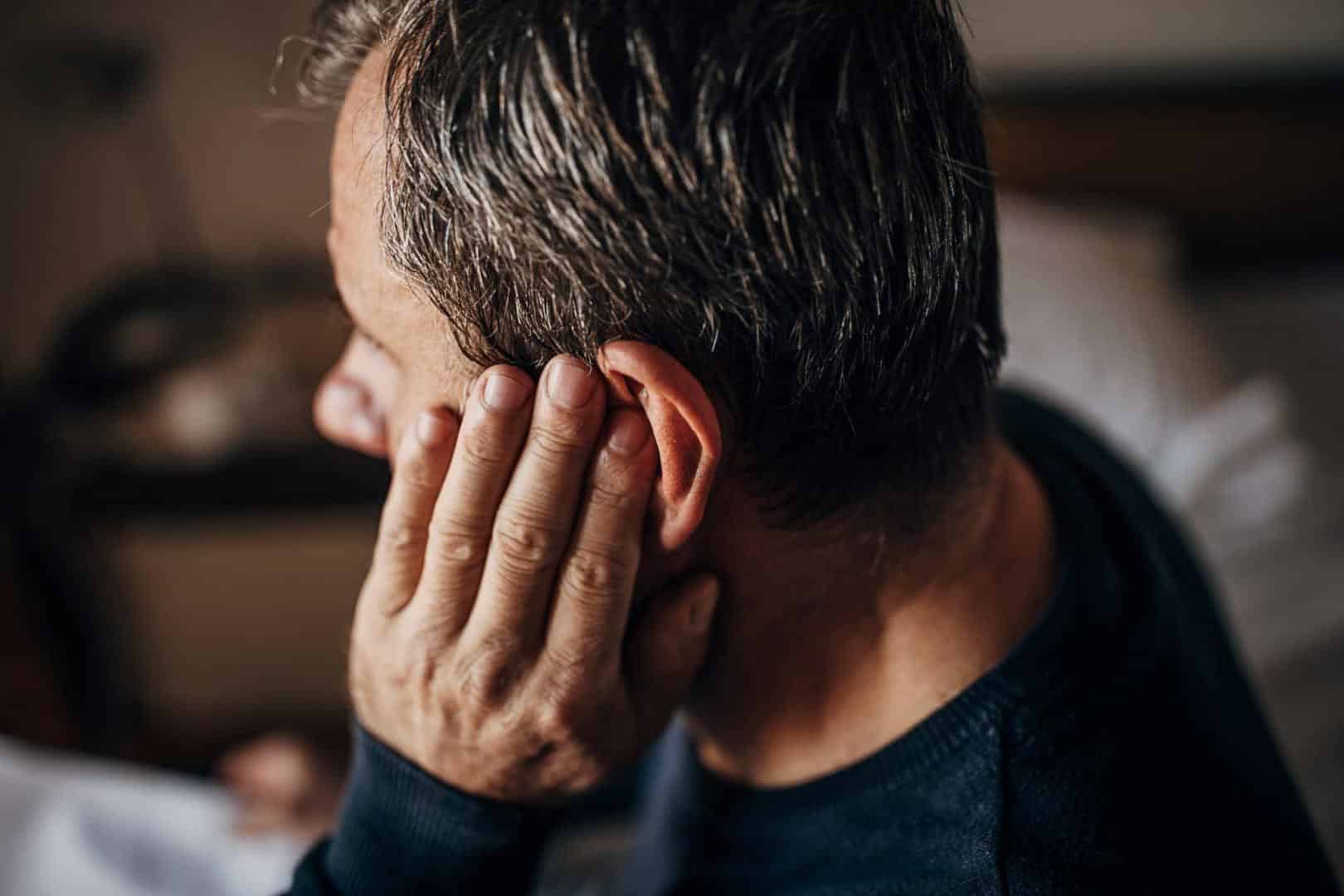 Man with ear pain rubbing his ear.