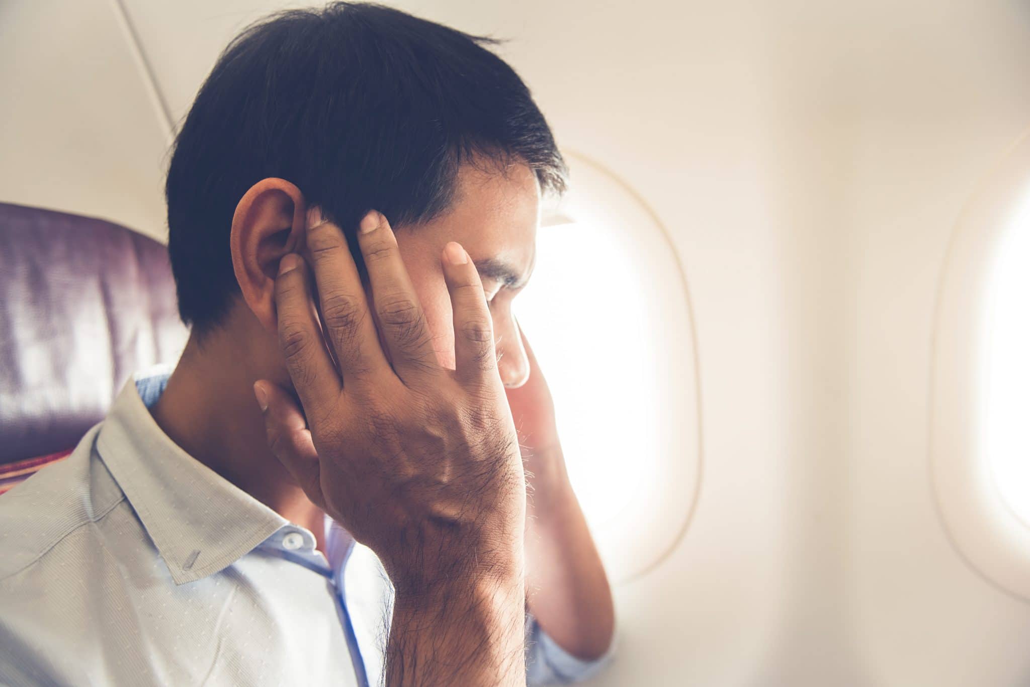 Male passenger having ear pop on the airplane while taking off (or landing)