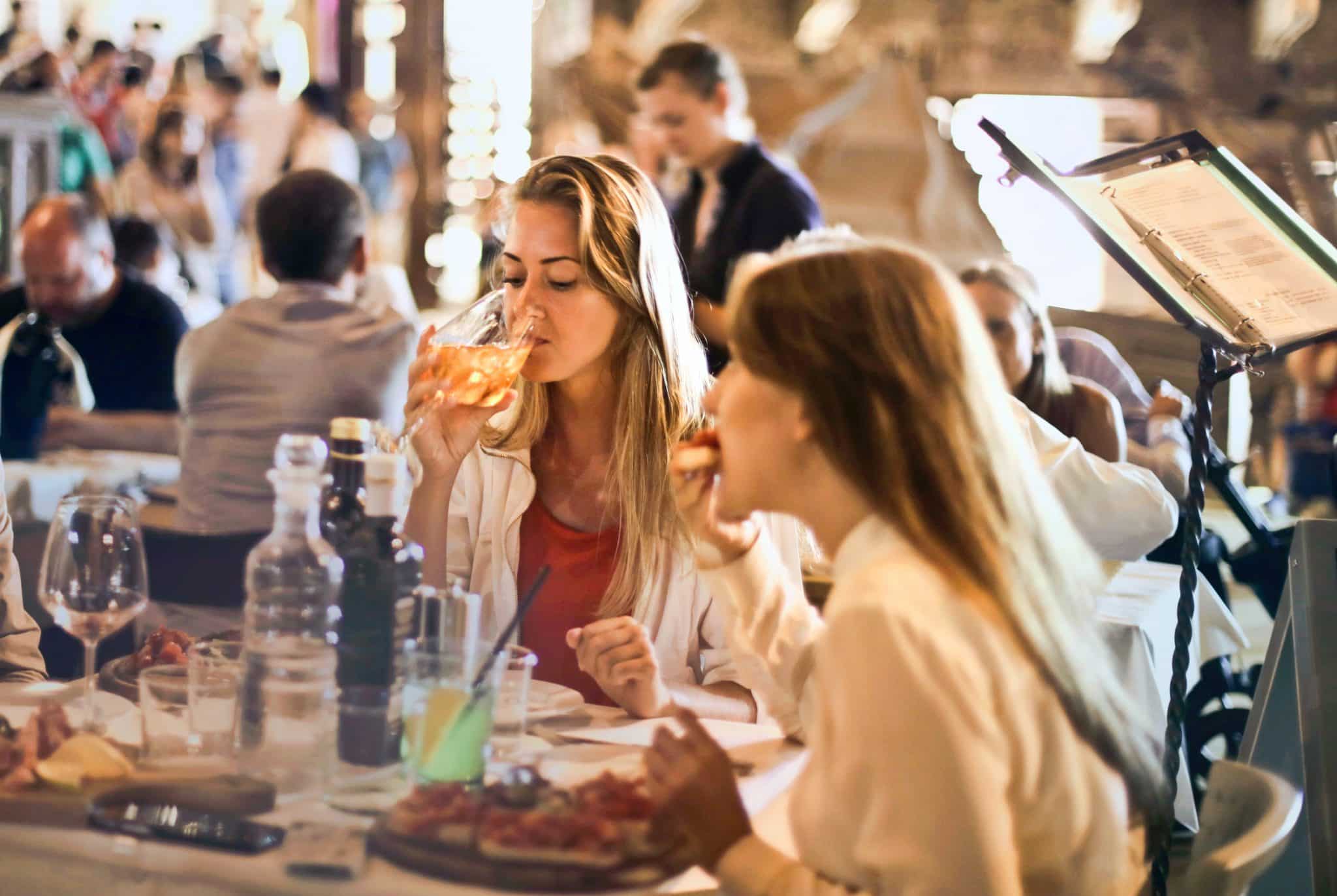 Two women dining in a busy restaurant.