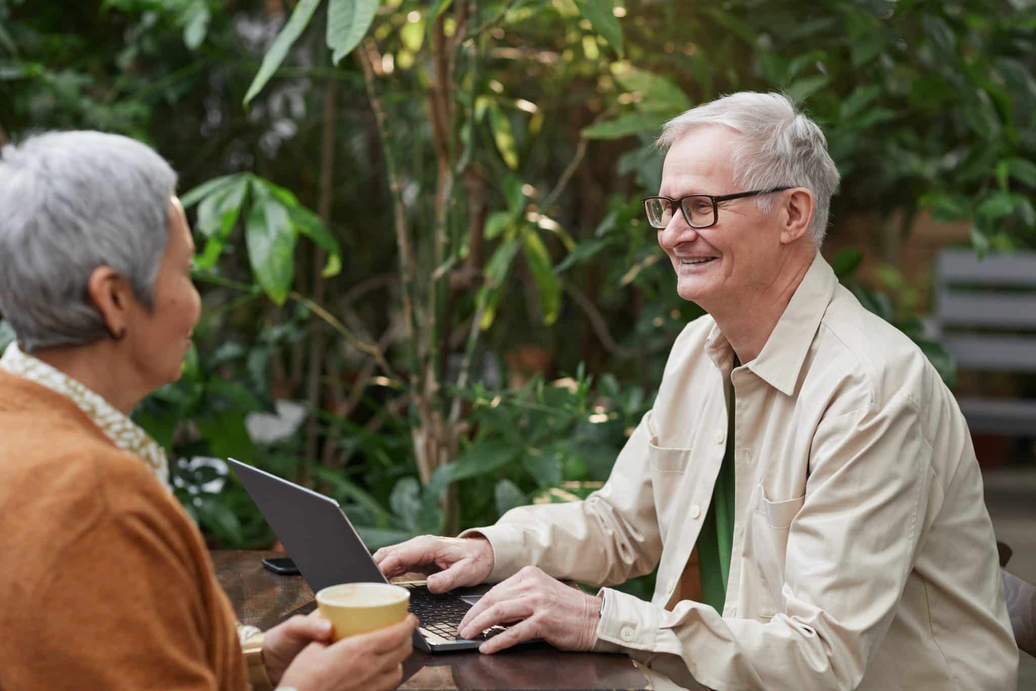 Older couple enjoying conversation at an outdoor cafe.