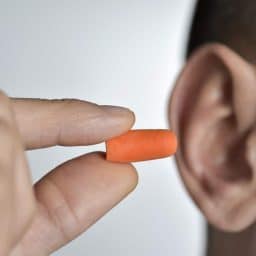 Man inserting an earplug for hearing protection.