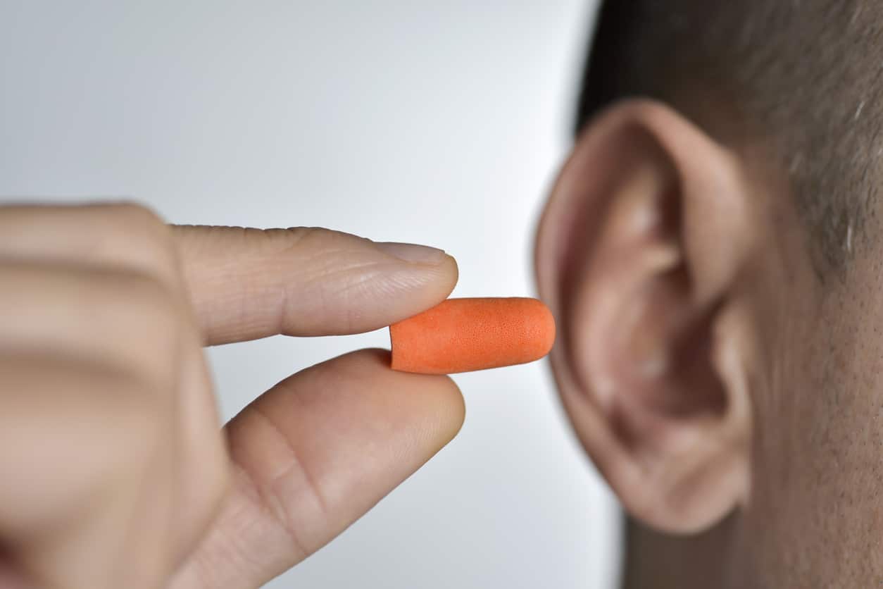 Man inserting an earplug for hearing protection.