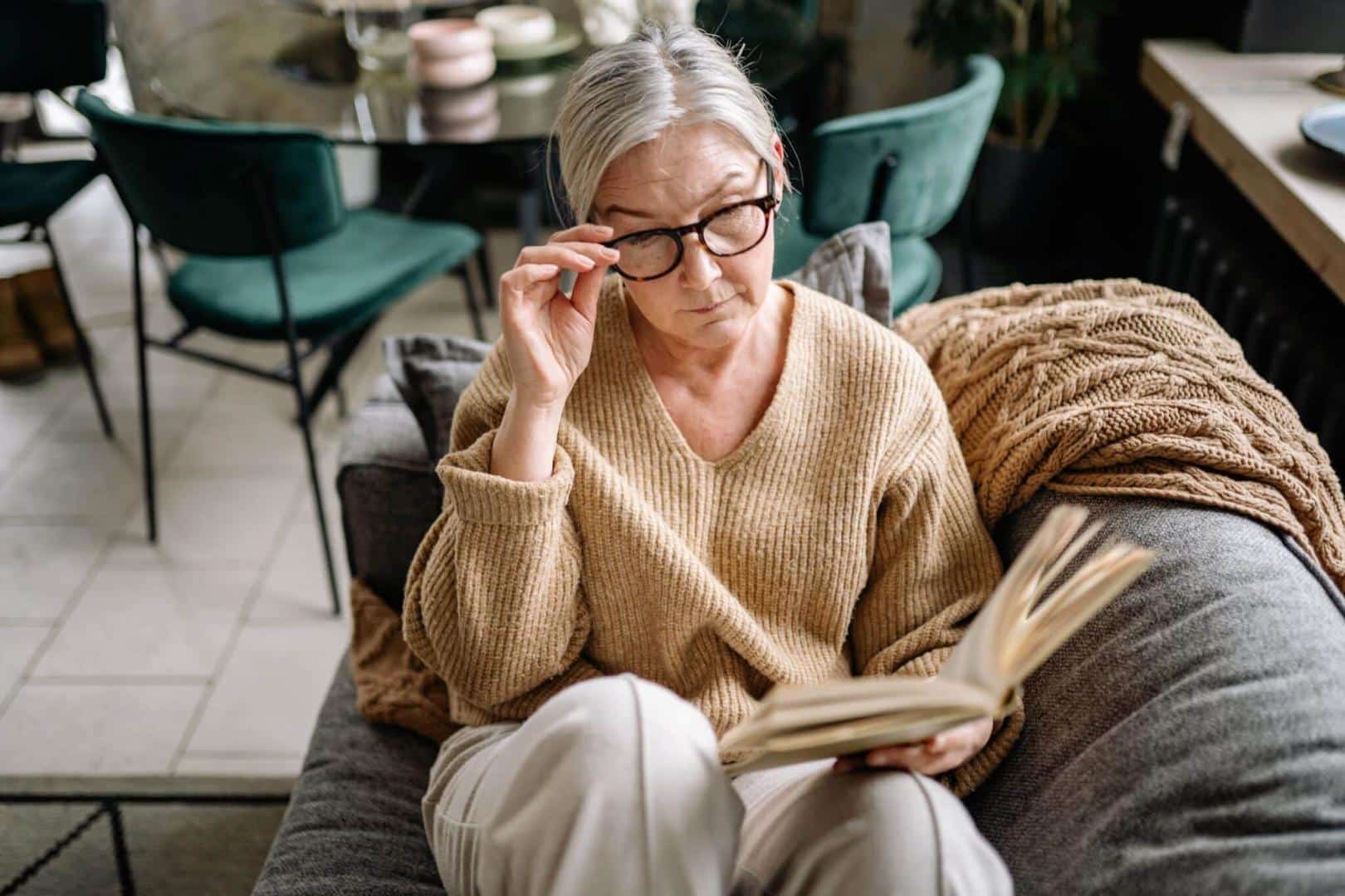 Older woman with glasses reading at home.