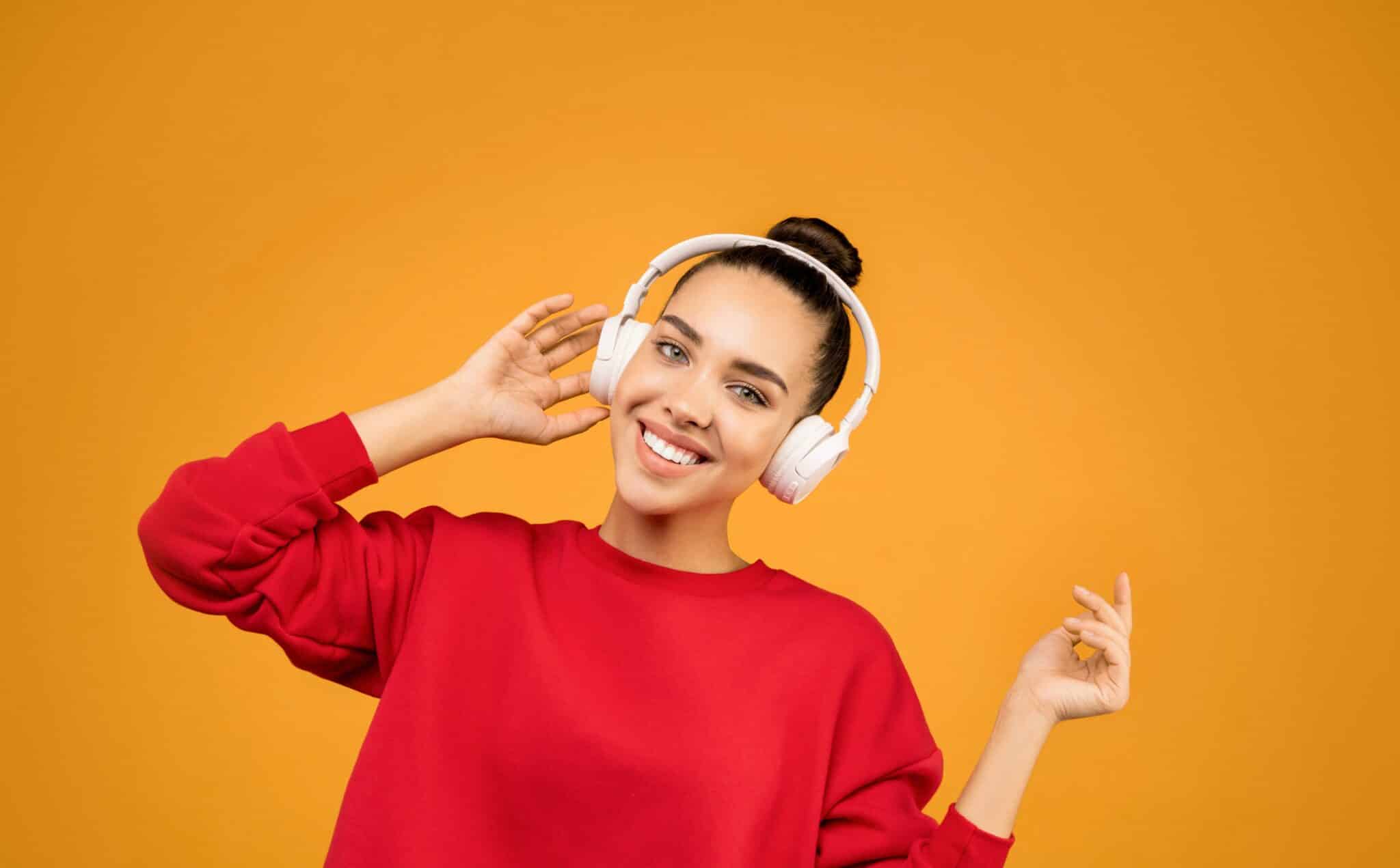 Woman in a red sweater wearing headphones.