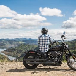 Man on a motorcycle looking out onto a scenic landscape.