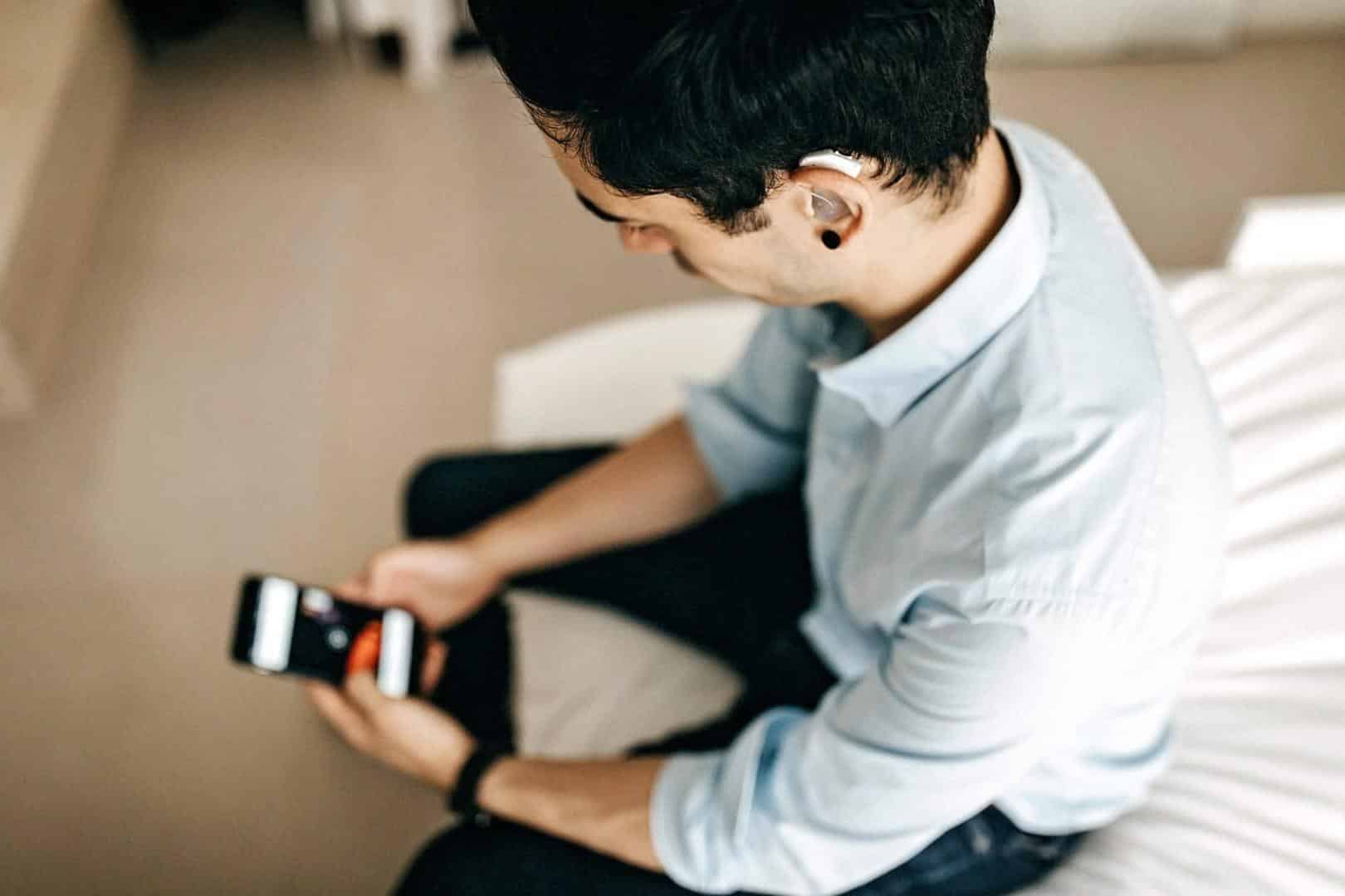 Man with hearing aids looking at his smartphone.