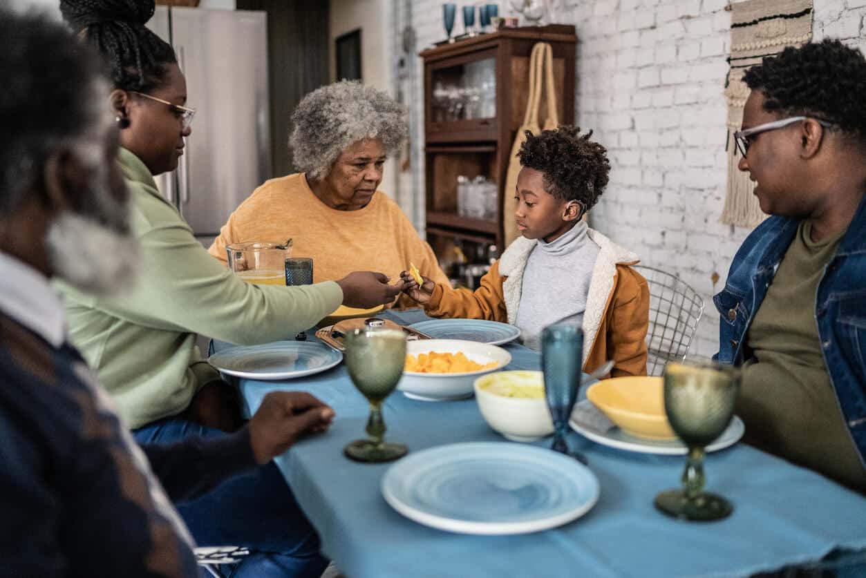 Family eating dinner together, young boy wearing hearing aid.