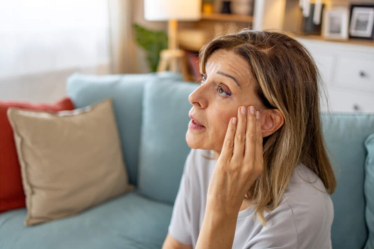 Woman with tinnitus holds ear 