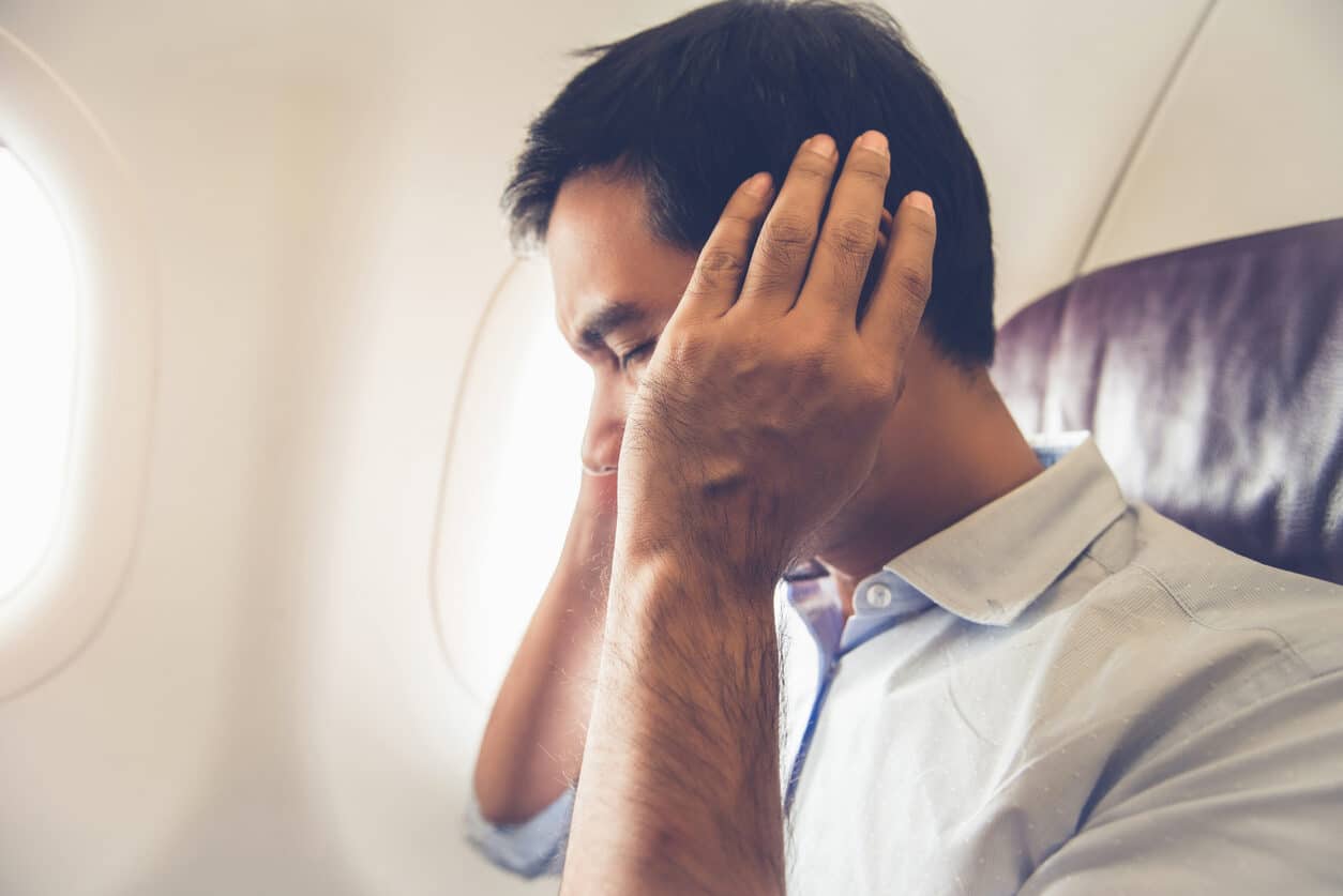 Man covers ears on a plane