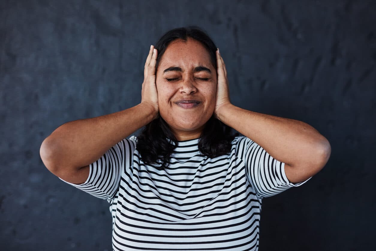 Woman experiencing tinnitus looking uncomfortable.