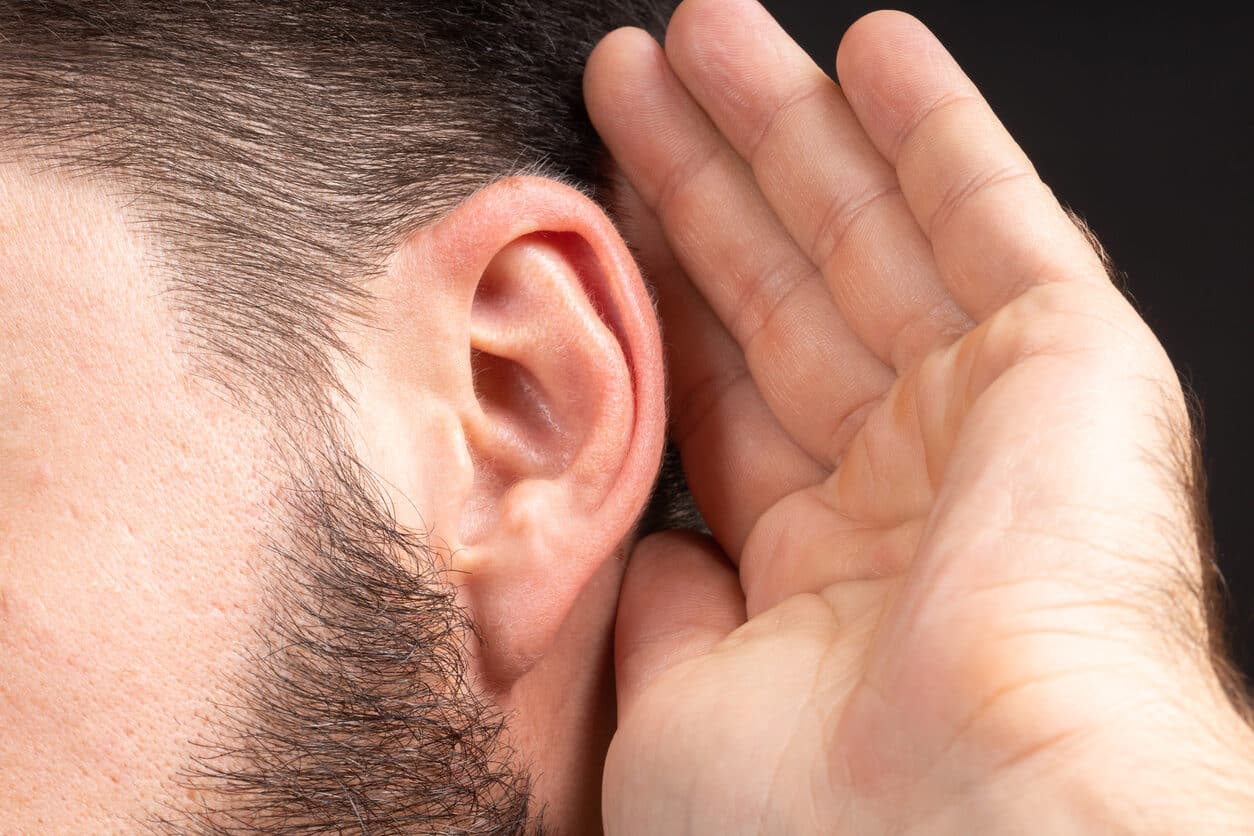 side of mans face his hand is held up to his ear because he is listening